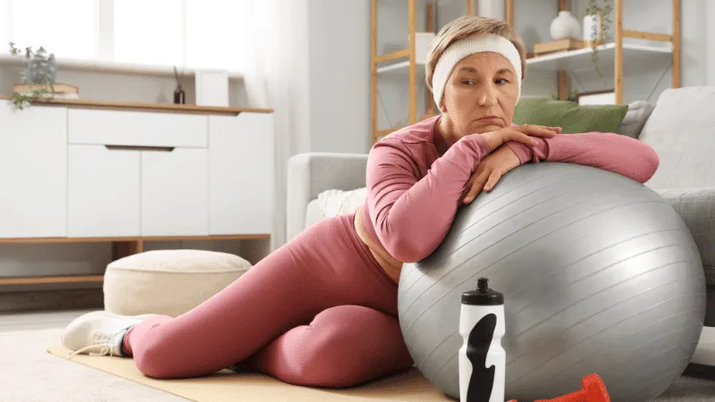 Woman in activewear resting against an exercise ball after a workout