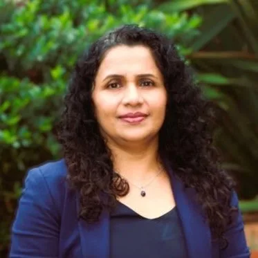 Dietitian with long dark hair smiling outdoors in a navy top